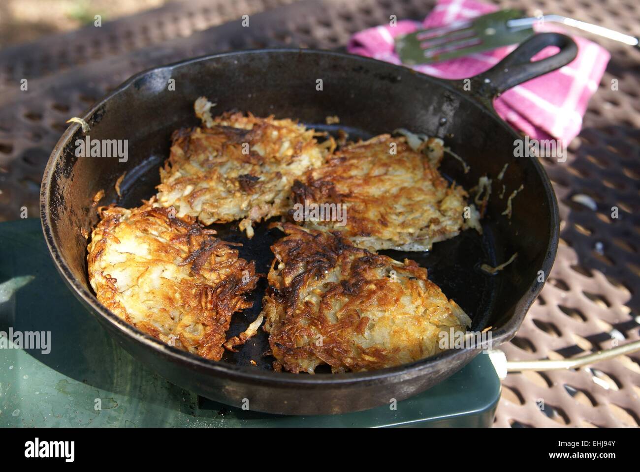 Golden fried shredded potato hash browns cooking in a cast iron skillet