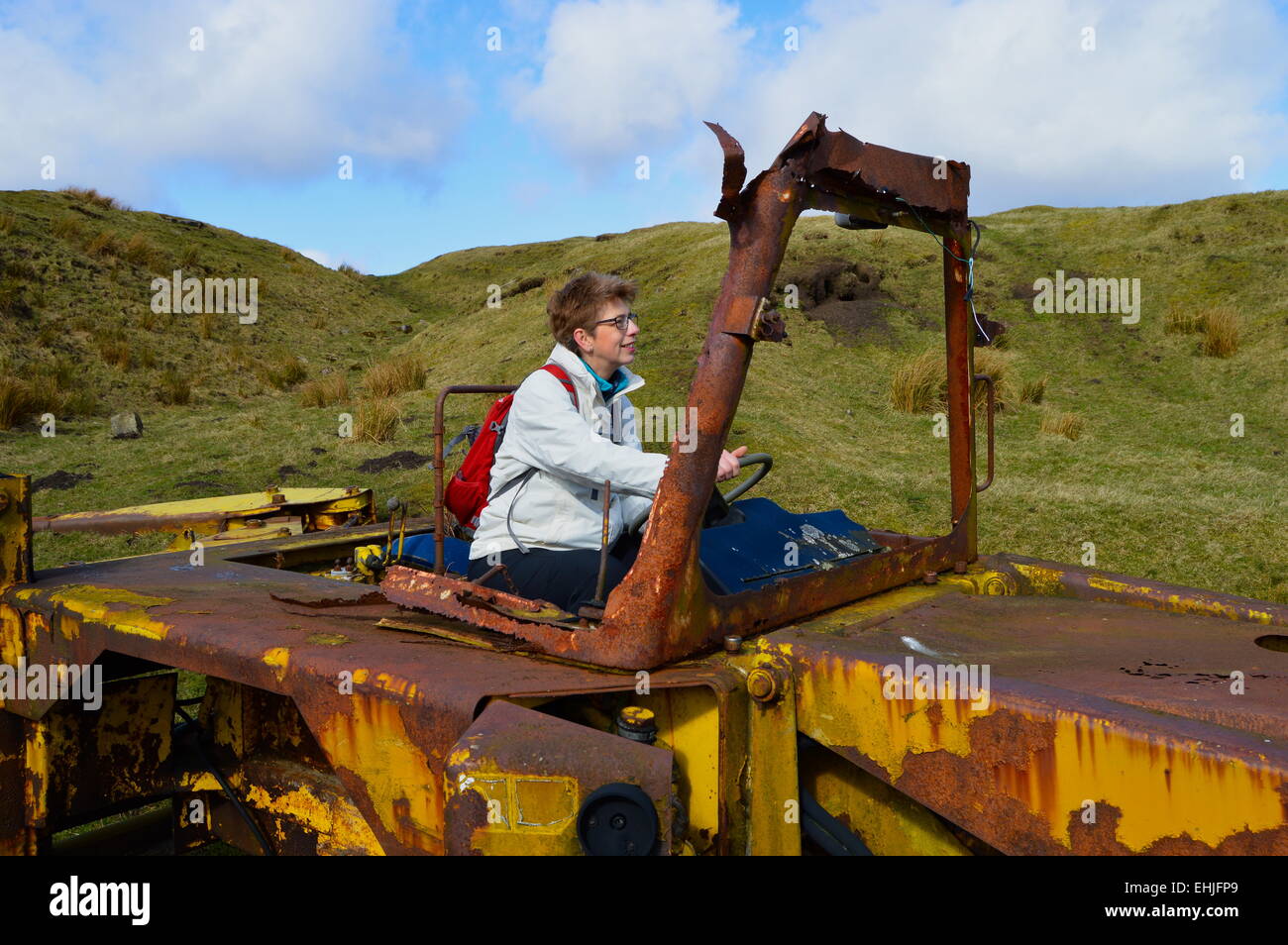 Woman driving old JCB digger on farmland on the Pennine Way. Stock Photo