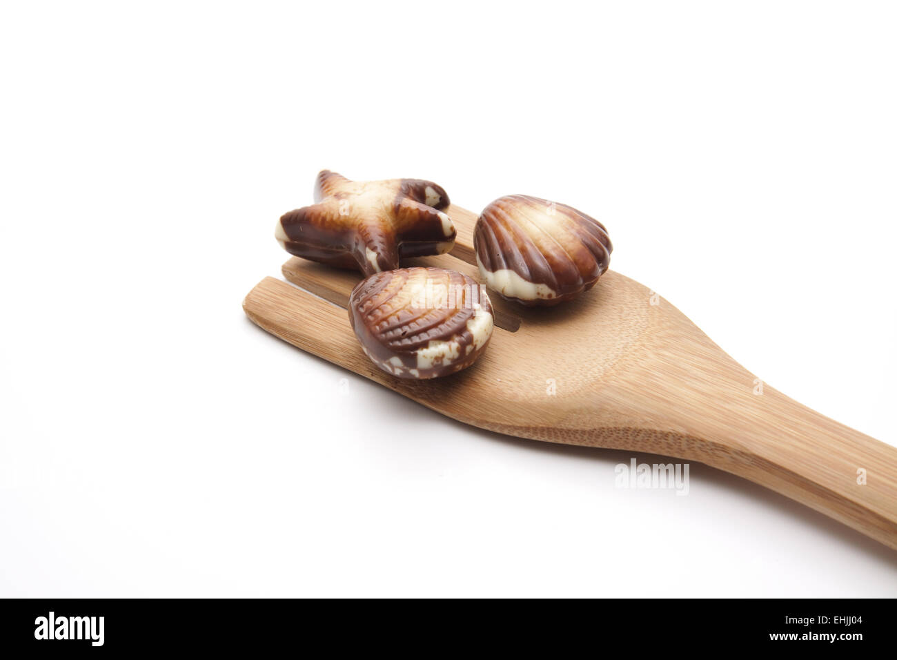 Mussel chocolates on wooden spoon Stock Photo