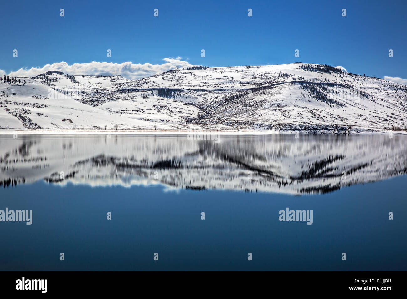 Reflection of snowy mountains surrounding partial frozen Blue Mesa Reservoir near Gunnison Colorado USA Stock Photo