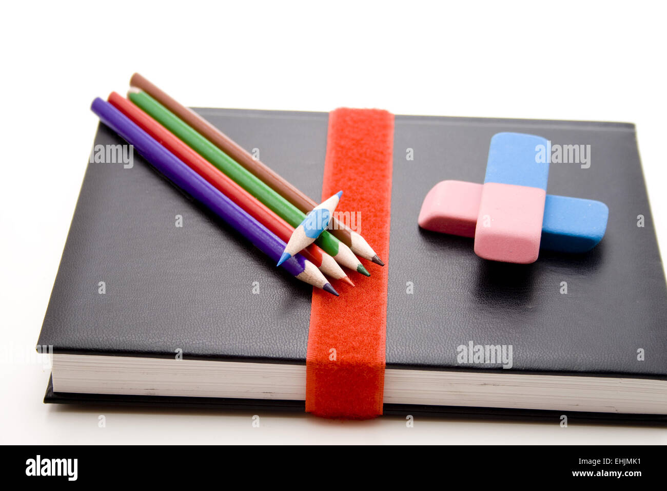 Colored pencils and erasers on book Stock Photo Alamy