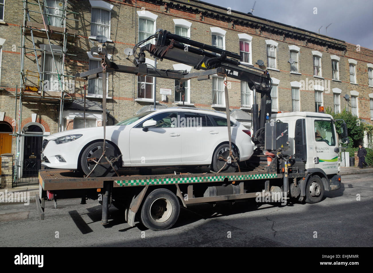car being towed away on a flat bed truck by local council enforcement team in London England UK Stock Photo