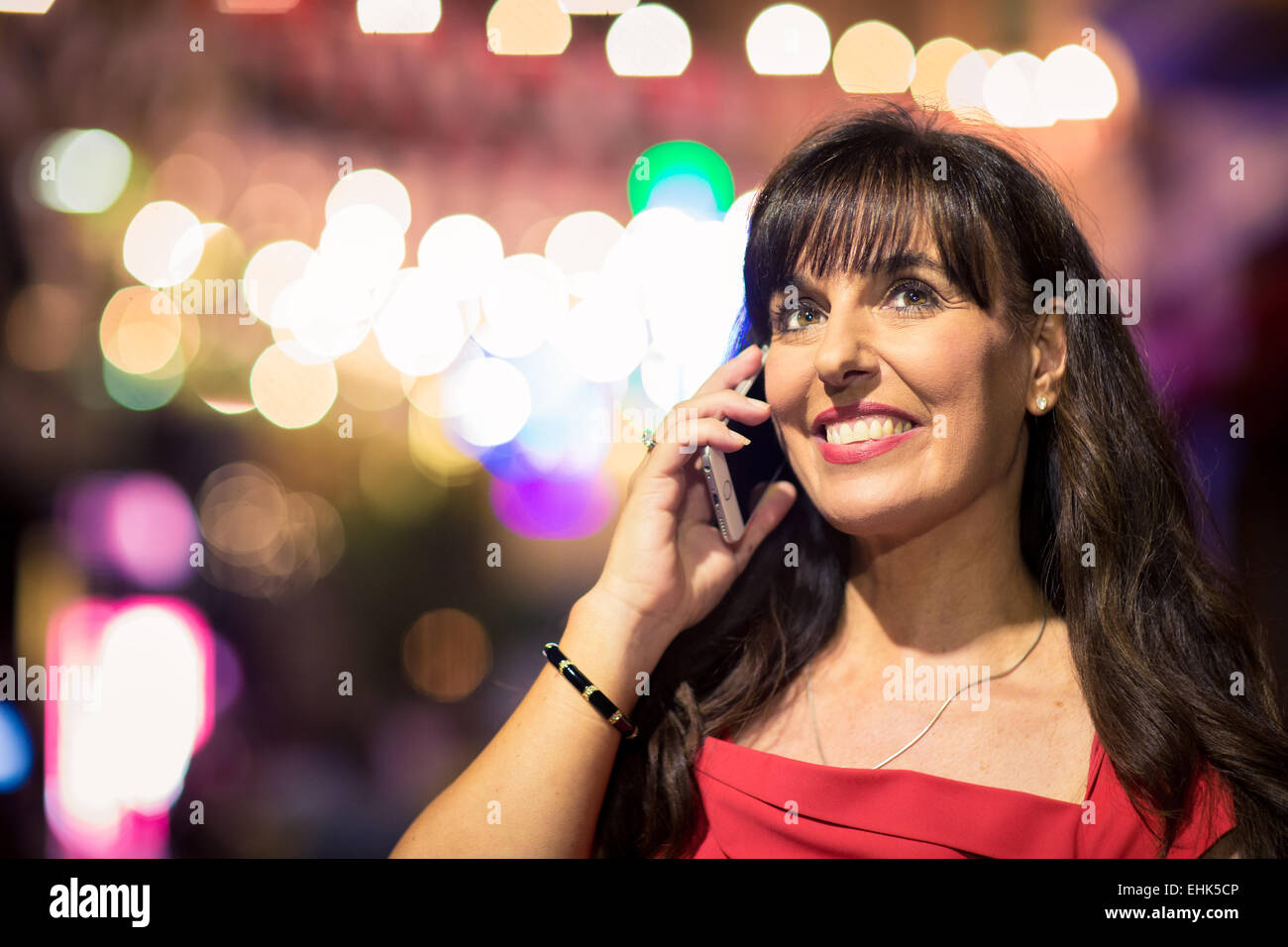 A woman in her 40's on her mobile device during a night out Stock Photo