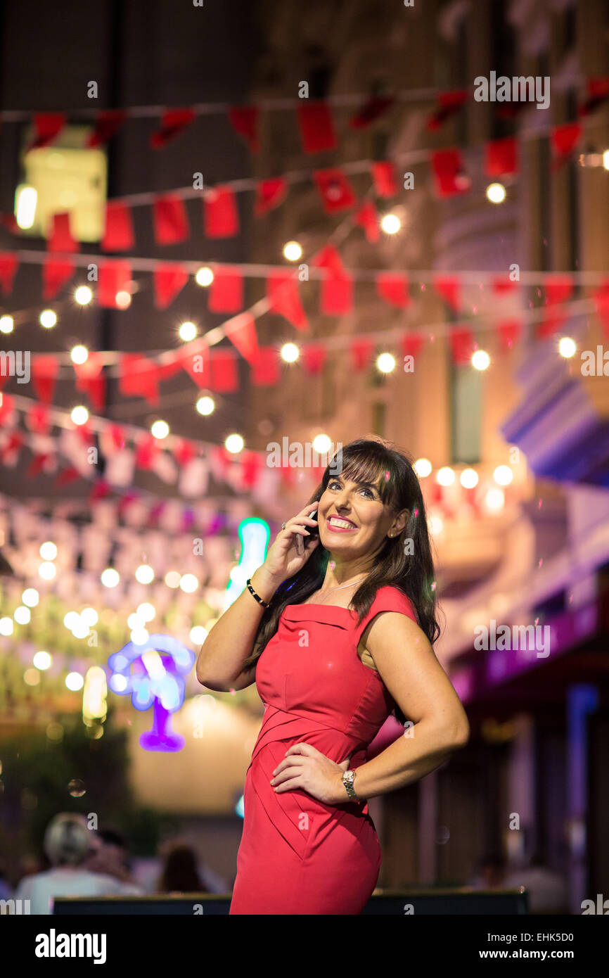 A woman in her 40's on her mobile device during a night out Stock Photo