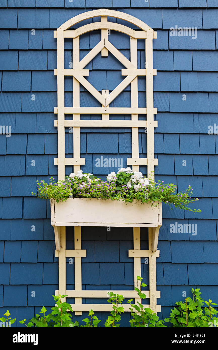 A decorative flower planter and trellis on the side of an older style home. Stock Photo