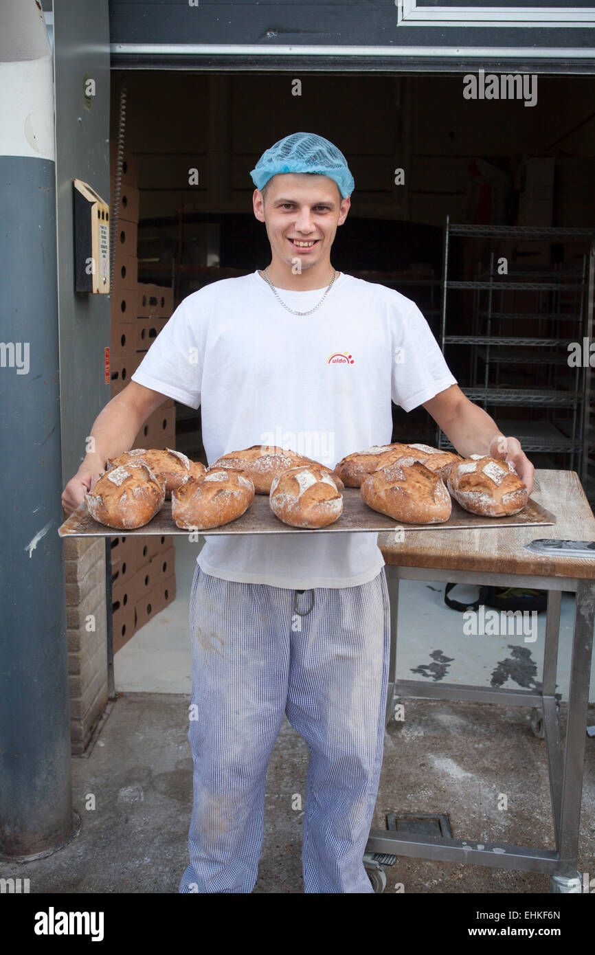 Baker holding a tray of loaves of freshly baked wholemeal bread Stock Photo