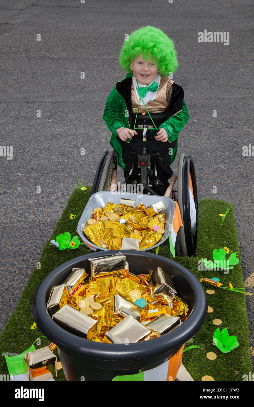 St. Patrick's Day Wheelchair user at Manchester, UK 15th March, 2015.  Wheelchair bound Daiton Berry Mellor 6 years old, a Spina bifida sufferer at the weekend Irish Festival. His dad has made a float as a Wheelbarrow full of gold coins and treasure.  The colourful procession set off from the Irish World Heritage Centre in Cheetham Hill before making its way to Albert Square.  Flag bearers representing the 32 counties in the Emerald Isle led the parade into the city centre, followed by floats from the city’s Irish associations. Stock Photo
