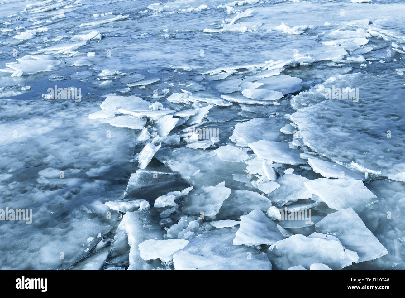Big ice fragments covered with show on frozen river water. Dark blue nature background Stock Photo