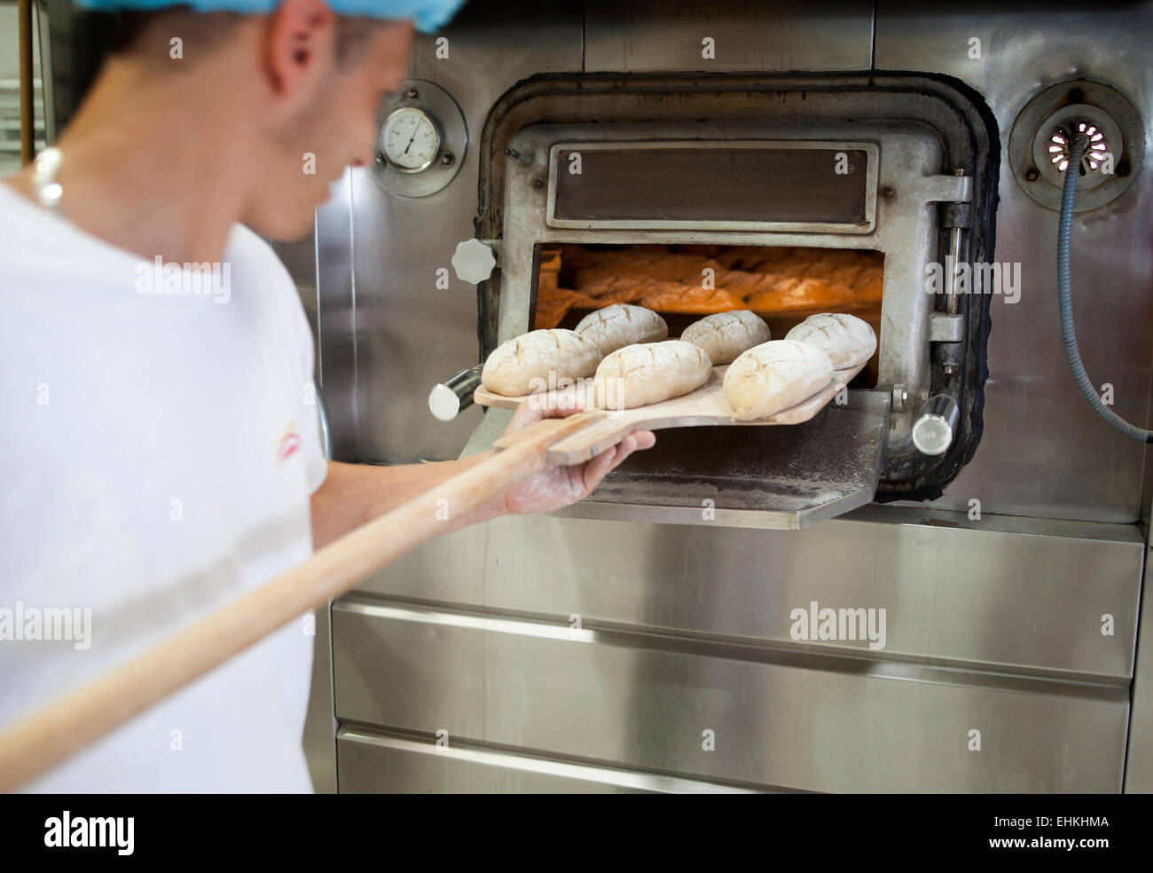 Baker putting loaves of bread into the oven Stock Photo Alamy