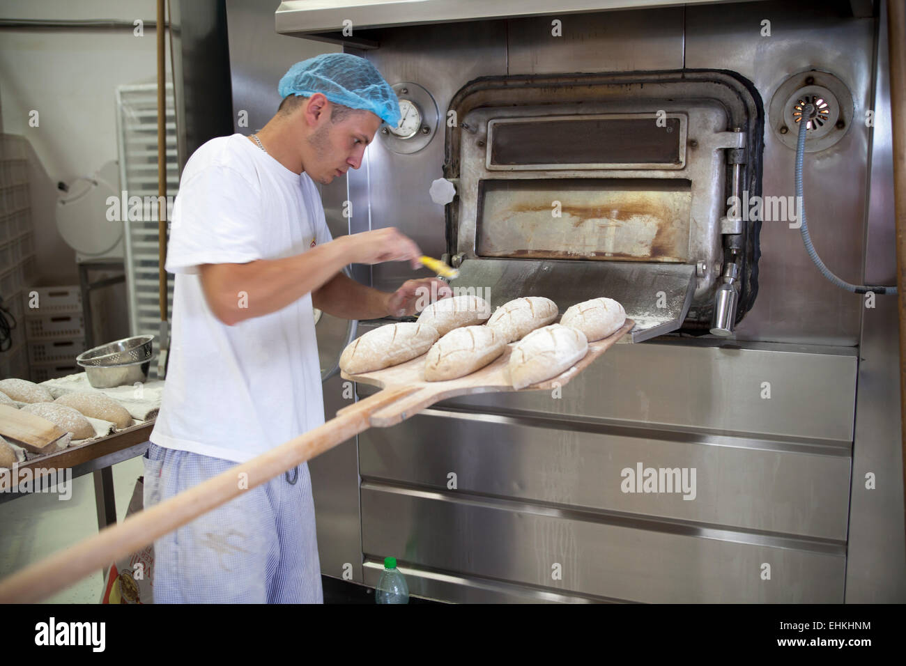 Baker preparing loaves of bread on paddle before placing in the oven