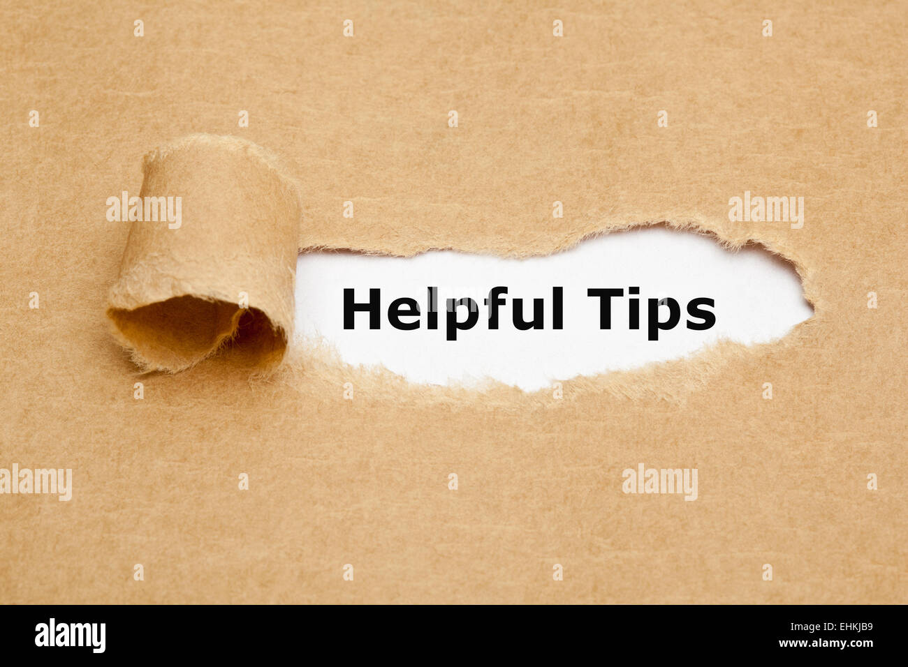 The text Helpful Tips appearing behind torn brown paper. Stock Photo
