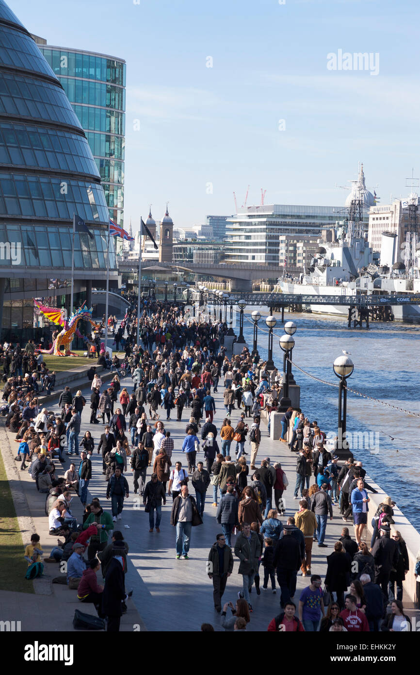 Crowds walking alongside the Thames on a sunny weekend. view of City Hall from Tower Bridge Stock Photo