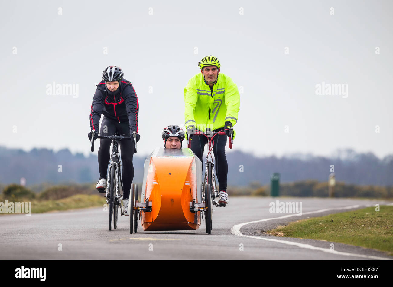 Two cyclists following behind a four wheeled recumbent cycle and rider in the New Forest National Park. Stock Photo