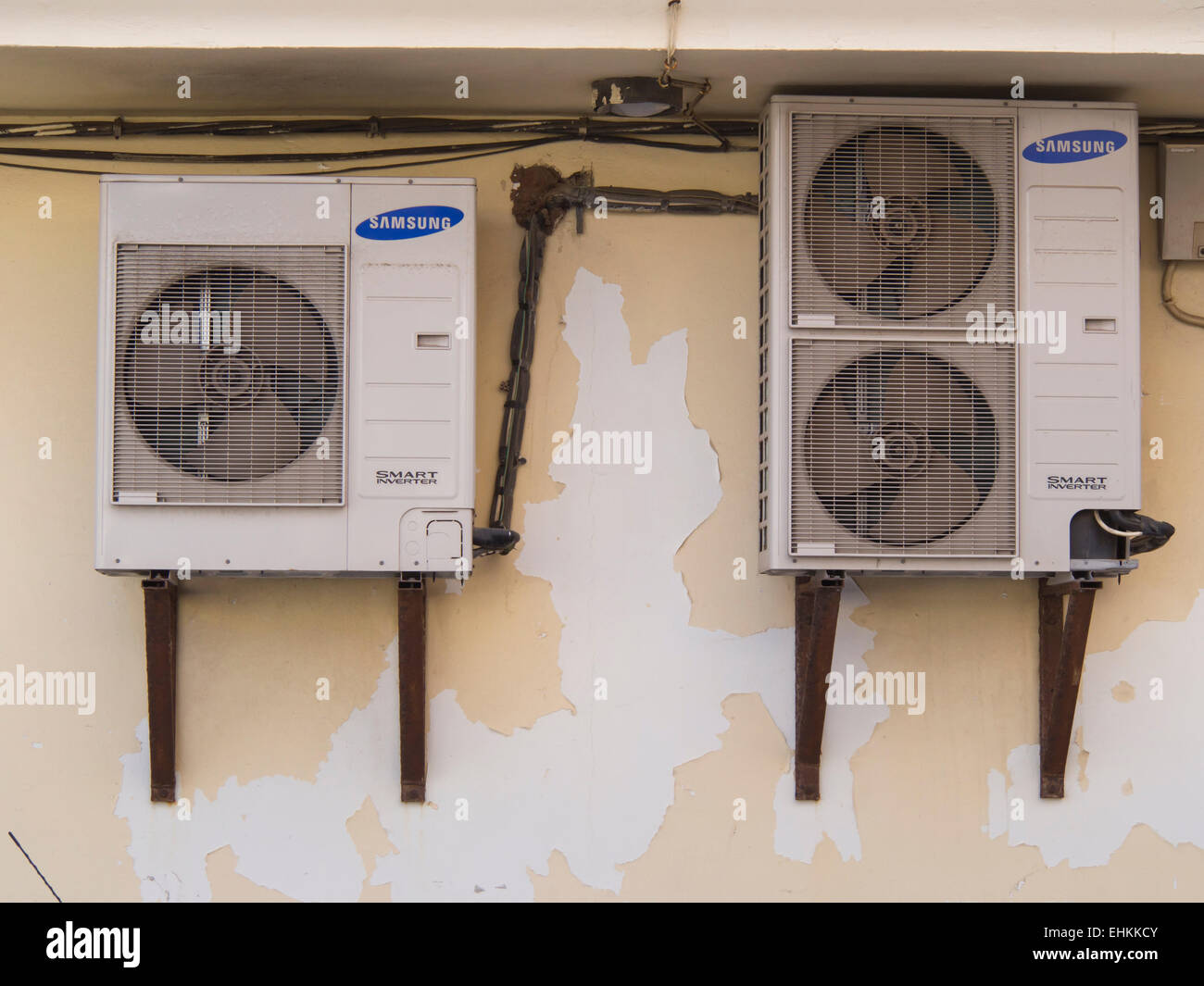 Electric air conditioning machines placed outside on a concrete building wall, necessary but not pretty, Coralejo Fuerteventura Stock Photo