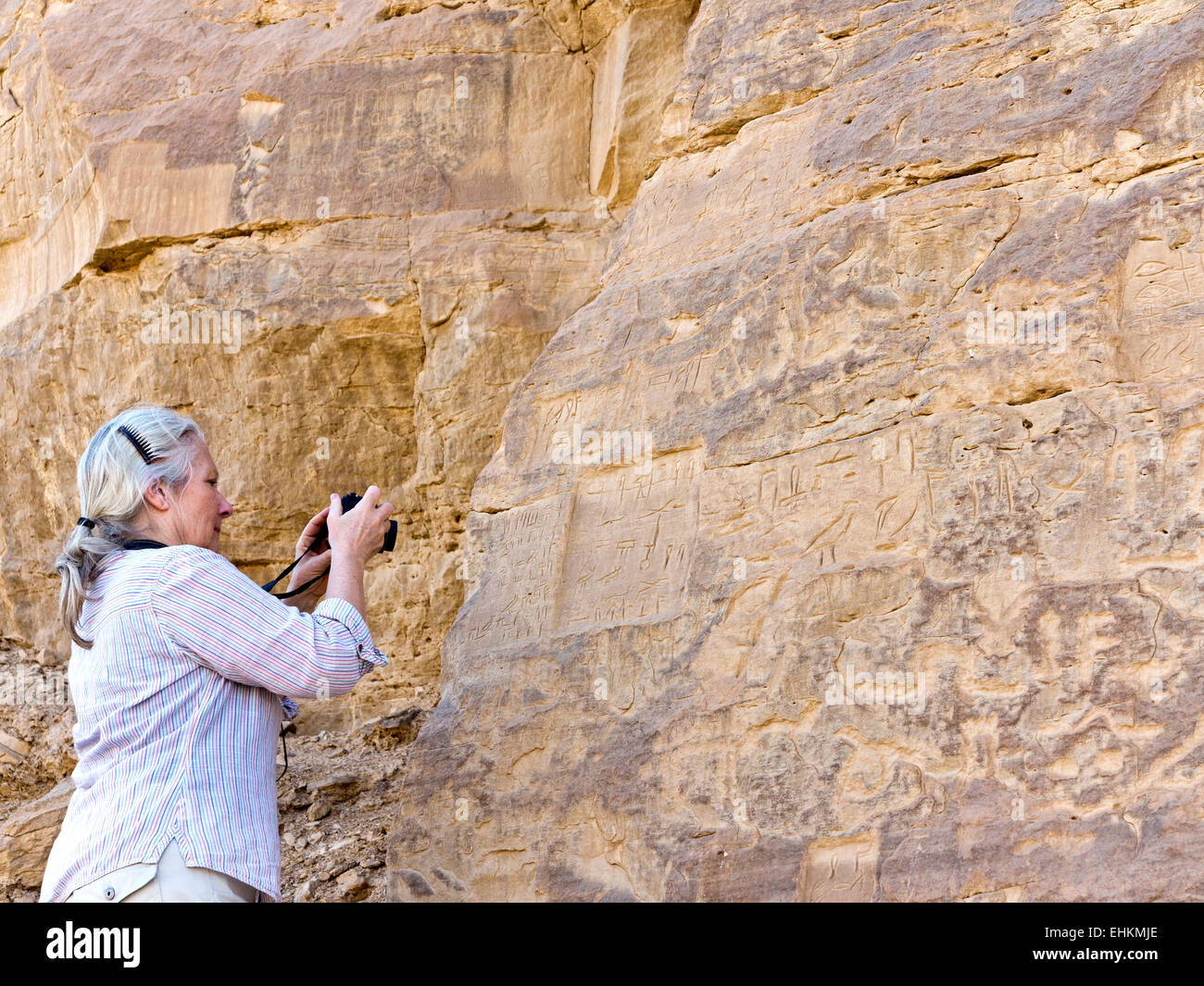 Female photographing rock art at Vulture Rock at the entrance to Wadi Hellal, el Kab, ancient Nekheb in Eastern Desert, Egypt Stock Photo