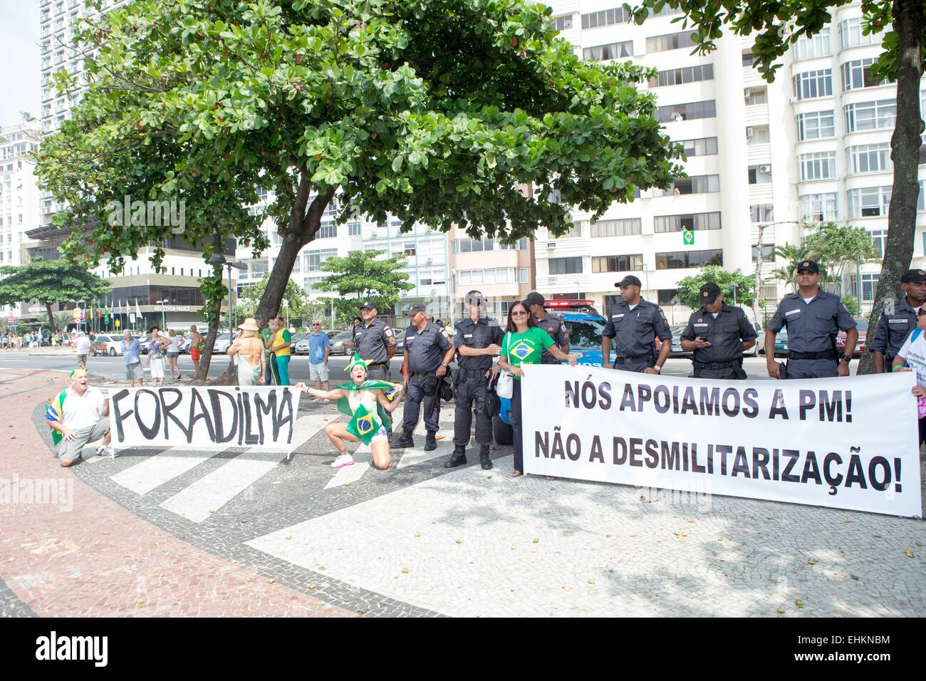 Rio De Janeiro, Brazil. 15th Mar, 2015. Protesters stand near a group of patrolling military police with placards written 'Out Dilma' and 'We support Military Police, not demilitarization' during an anti-government demonstration in Rio de Janeiro, Brazil, March 15, 2015. A demonstration was held here at Copacabana beach on Sunday. Credit:  Xu Zijian/Xinhua/Alamy Live News Stock Photo