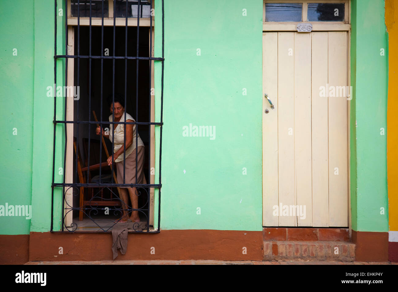 A woman sweeps her house in Trinidad, Cuba Stock Photo