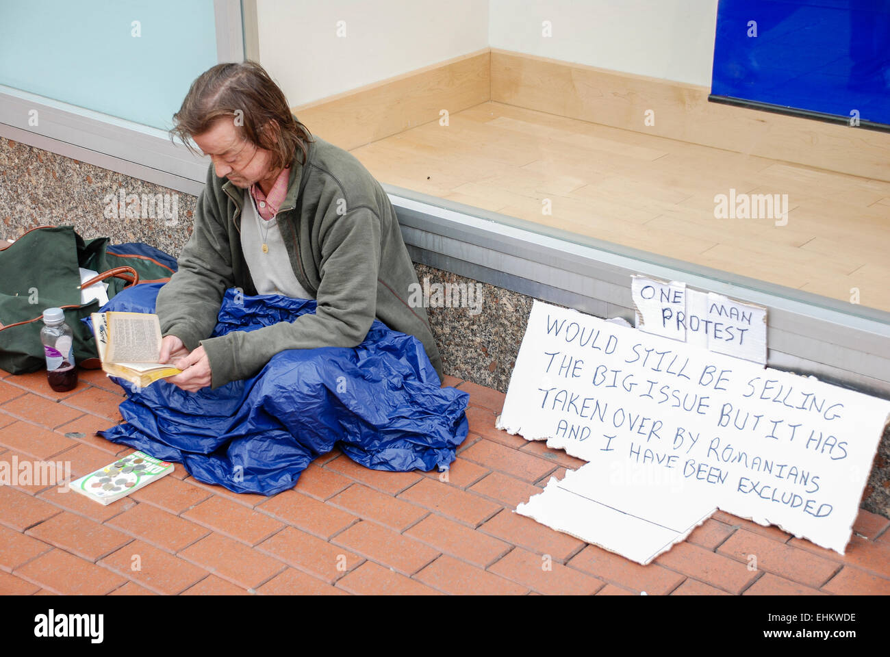 Homeless man sits on the footpath, protesting against gangs of professional Romanian beggers forcing him out of selling the Big Issue Stock Photo
