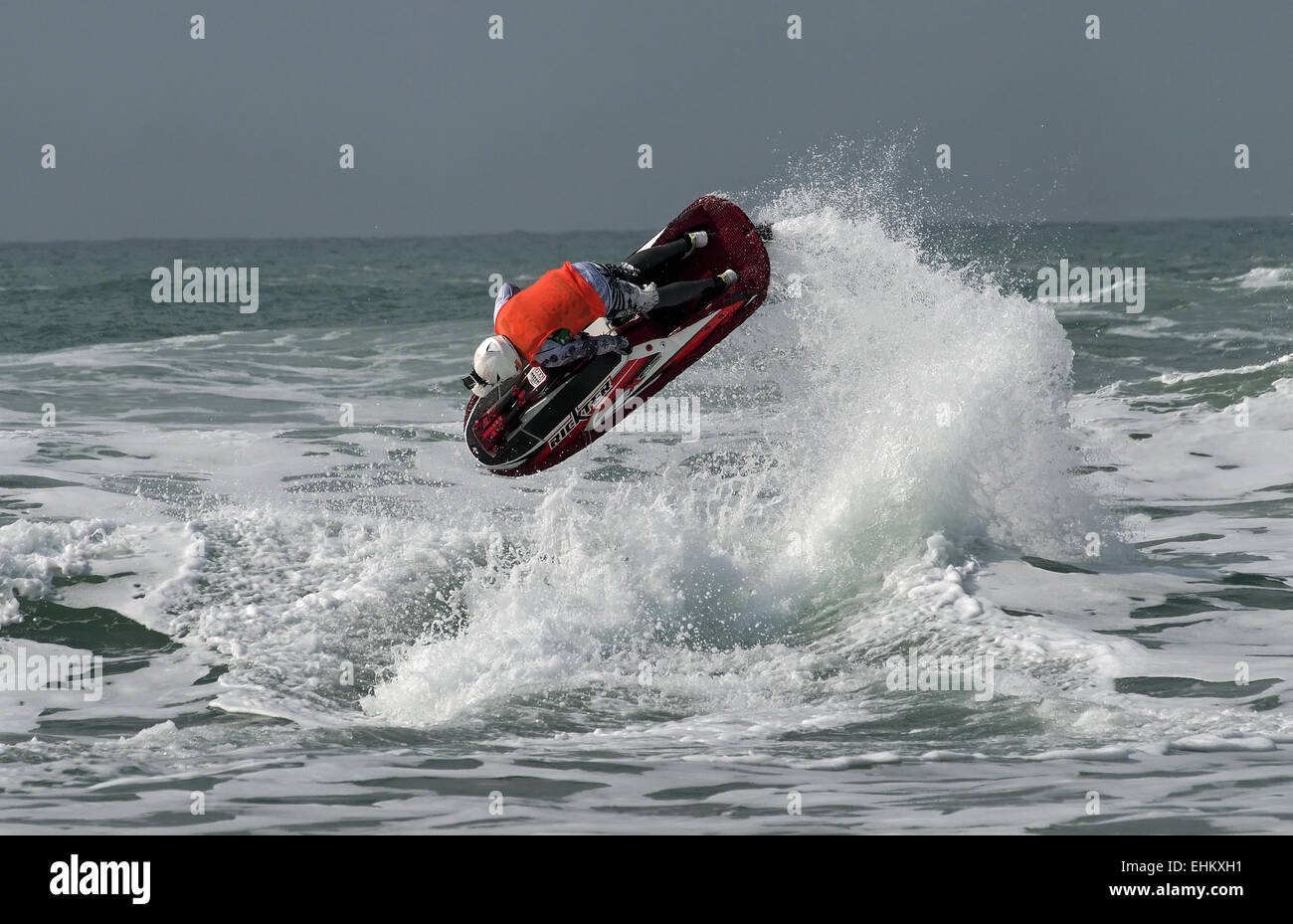 Male jet ski competitor performs aerial action moves in large breaking surf on Newquay Fistral