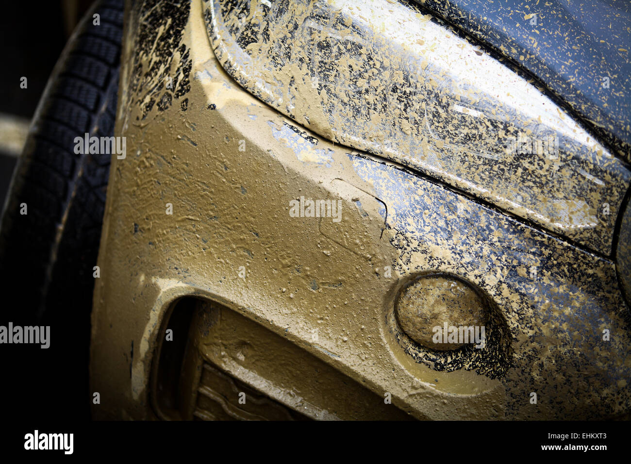 Color detail with the front side of an offroad car, covered in mud