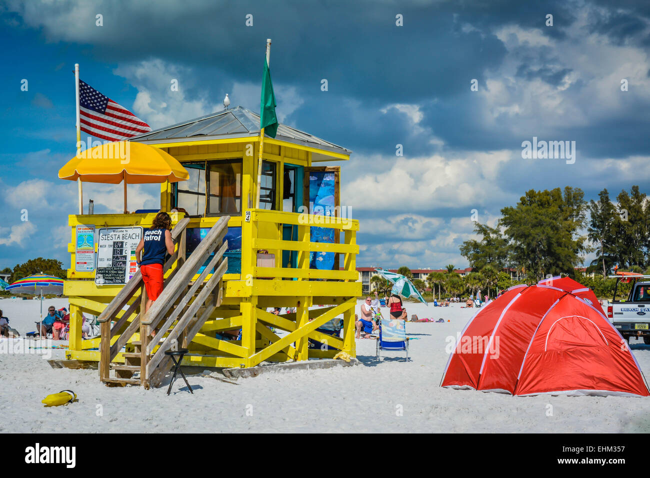 A life guard returns to his Siesta Key Beach station while beach goers enjoy the warm and cloudy day in Sarasota, Florida Stock Photo