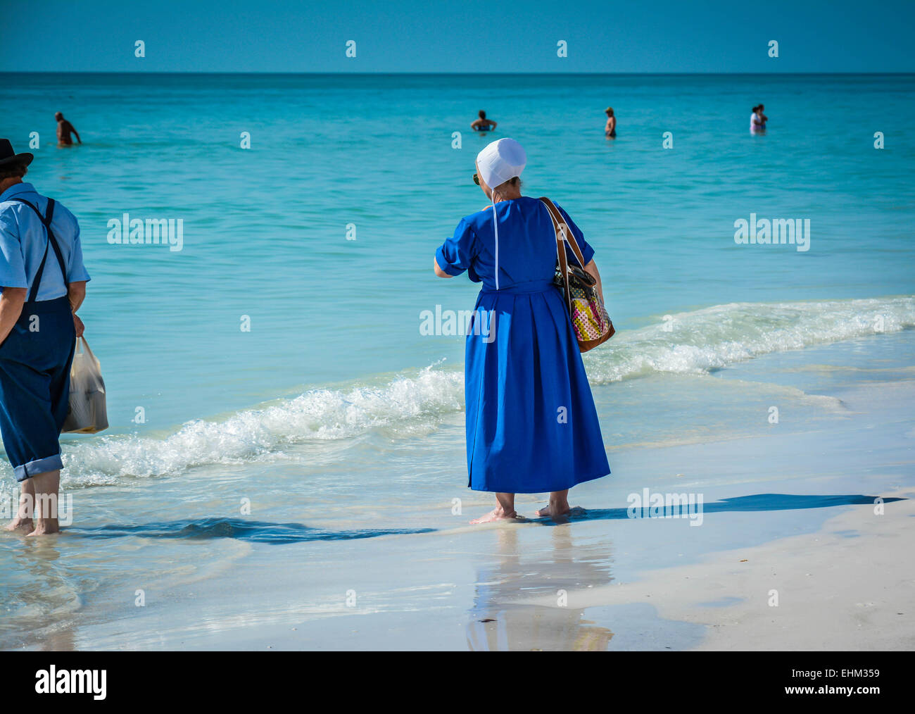 Amish people, dressed in their traditional manner paddle in the shallow ...