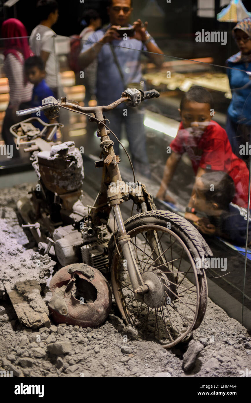 Bandung, Indonesia. 15th Mar, 2015. Children observe a damaged motorcycle hit by pyroclastic flows, at Geology Museum, Bandung, Indonesia. The artifact was taken from 2010 Mount Merapi eruption site in Yogyakarta province. Stock Photo