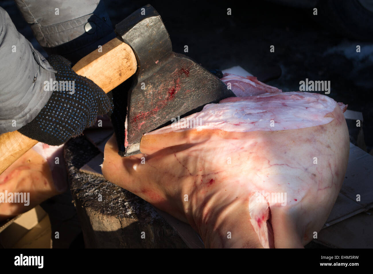 A butcher uses an axe to cut raw pork ready to sell Stock Photo