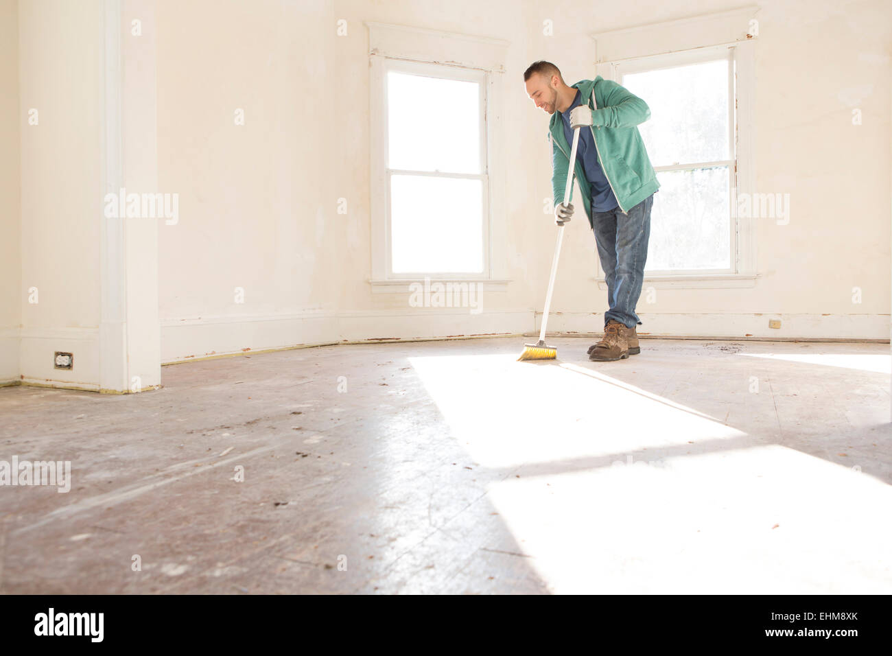 Mixed race man sweeping floor of new home Stock Photo
