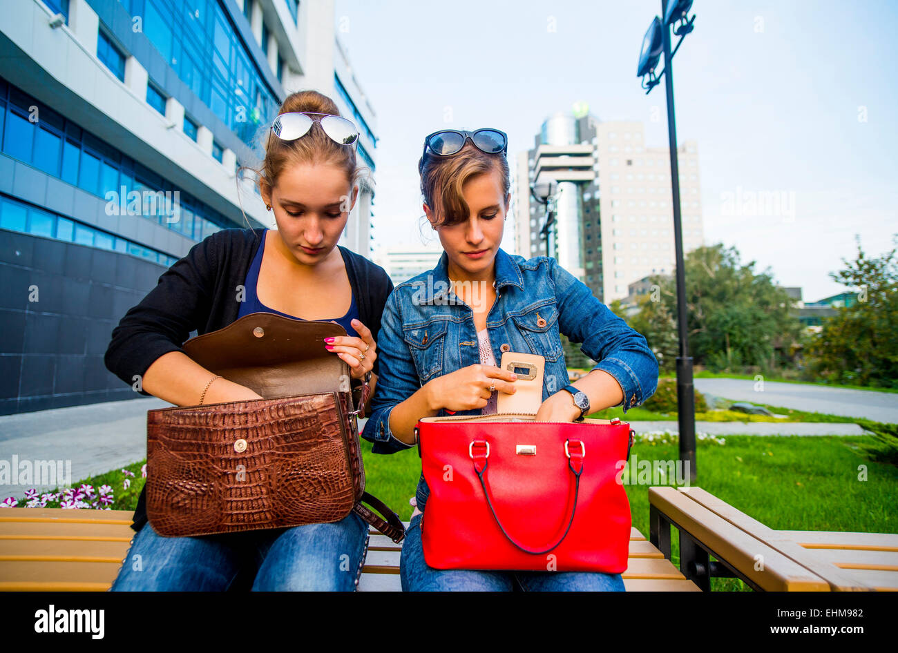 Caucasian women searching in purses on park bench Stock Photo