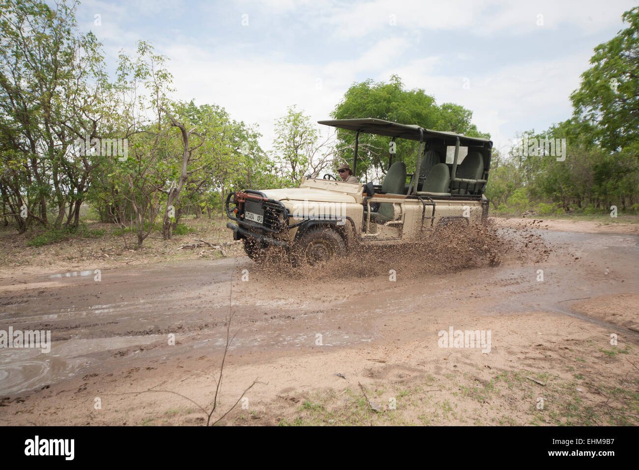 Game viewer splashing through the mud on safari in the Selous, in the rainy season. Stock Photo