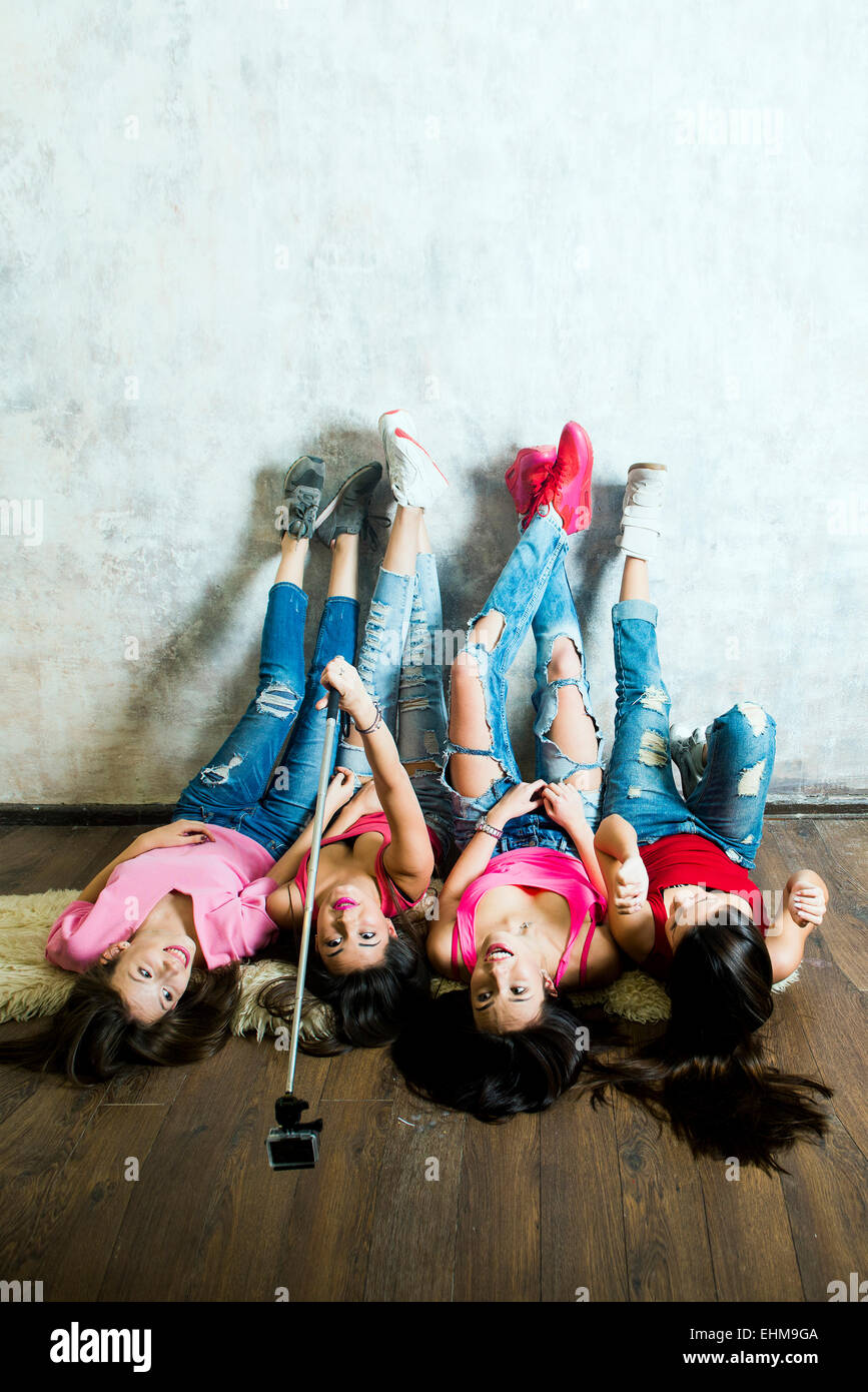 Caucasian women taking cell phone selfie on floor Stock Photo