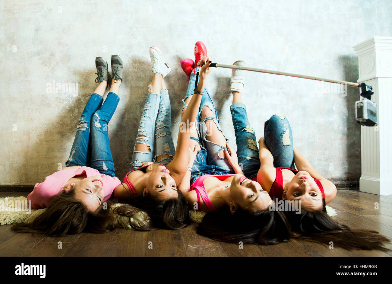 Caucasian women taking cell phone selfie on floor Stock Photo
