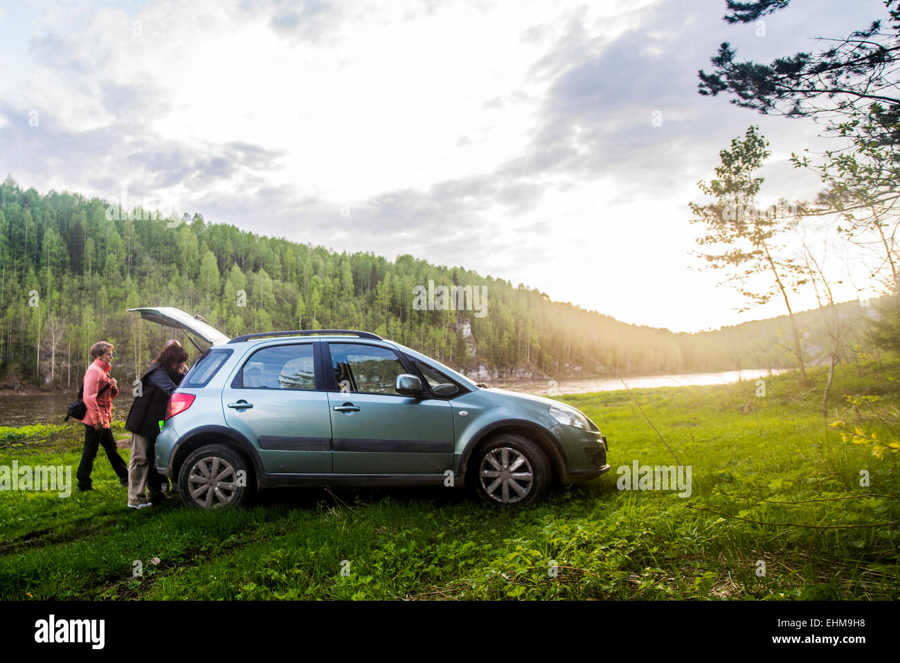 Caucasian tourists unloading car in remote landscape Stock Photo