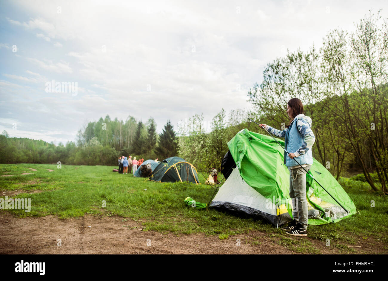 Caucasian camper assembling tent in remote field Stock Photo