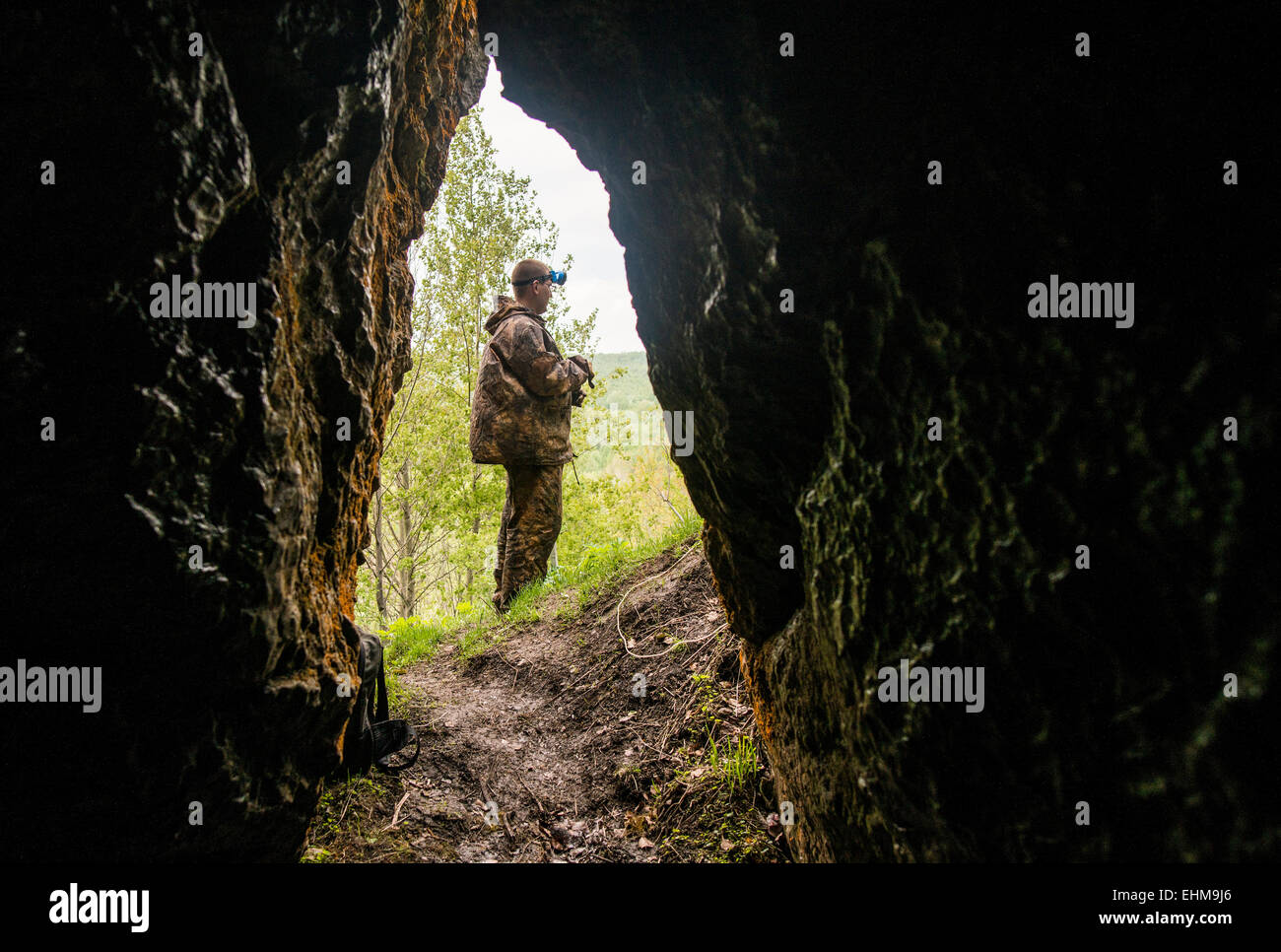 Caucasian man standing outside rock formation cave Stock Photo