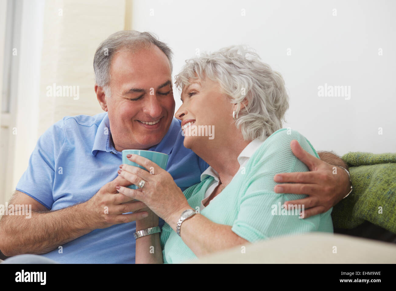 Older couple drinking coffee on sofa Stock Photo