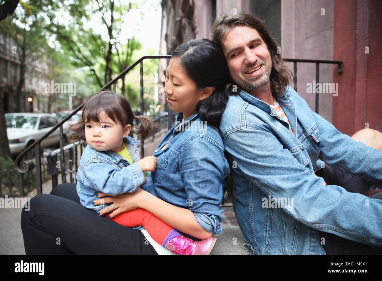 Family sitting on front stoop in city Stock Photo