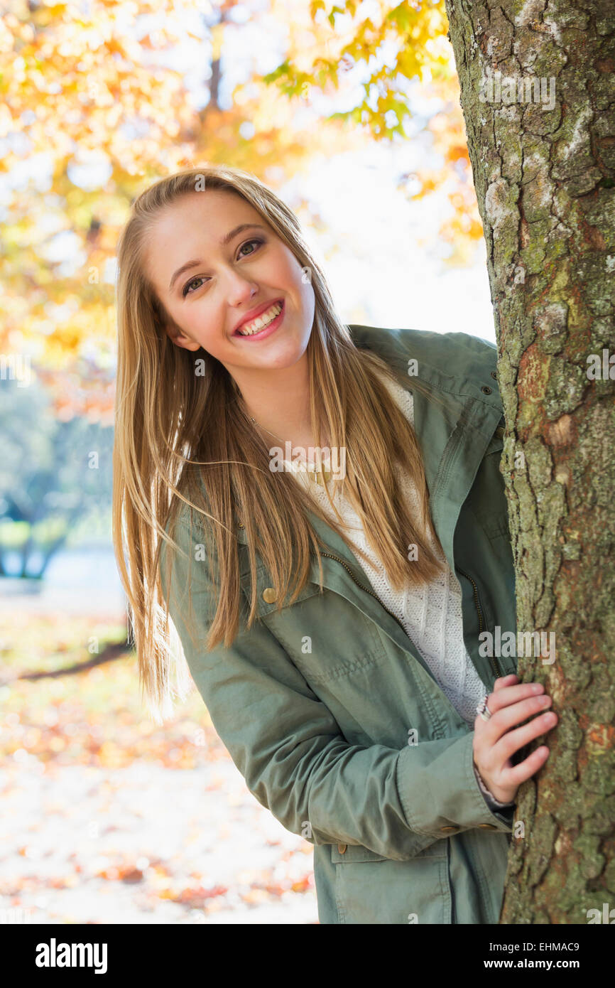 Caucasian woman peeking from behind tree Stock Photo