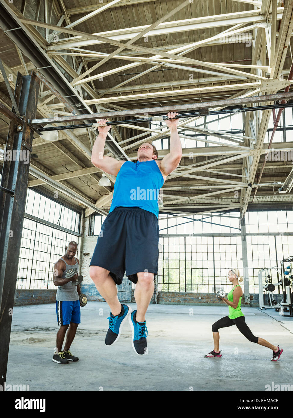 Athlete doing pull-ups in warehouse gym Stock Photo