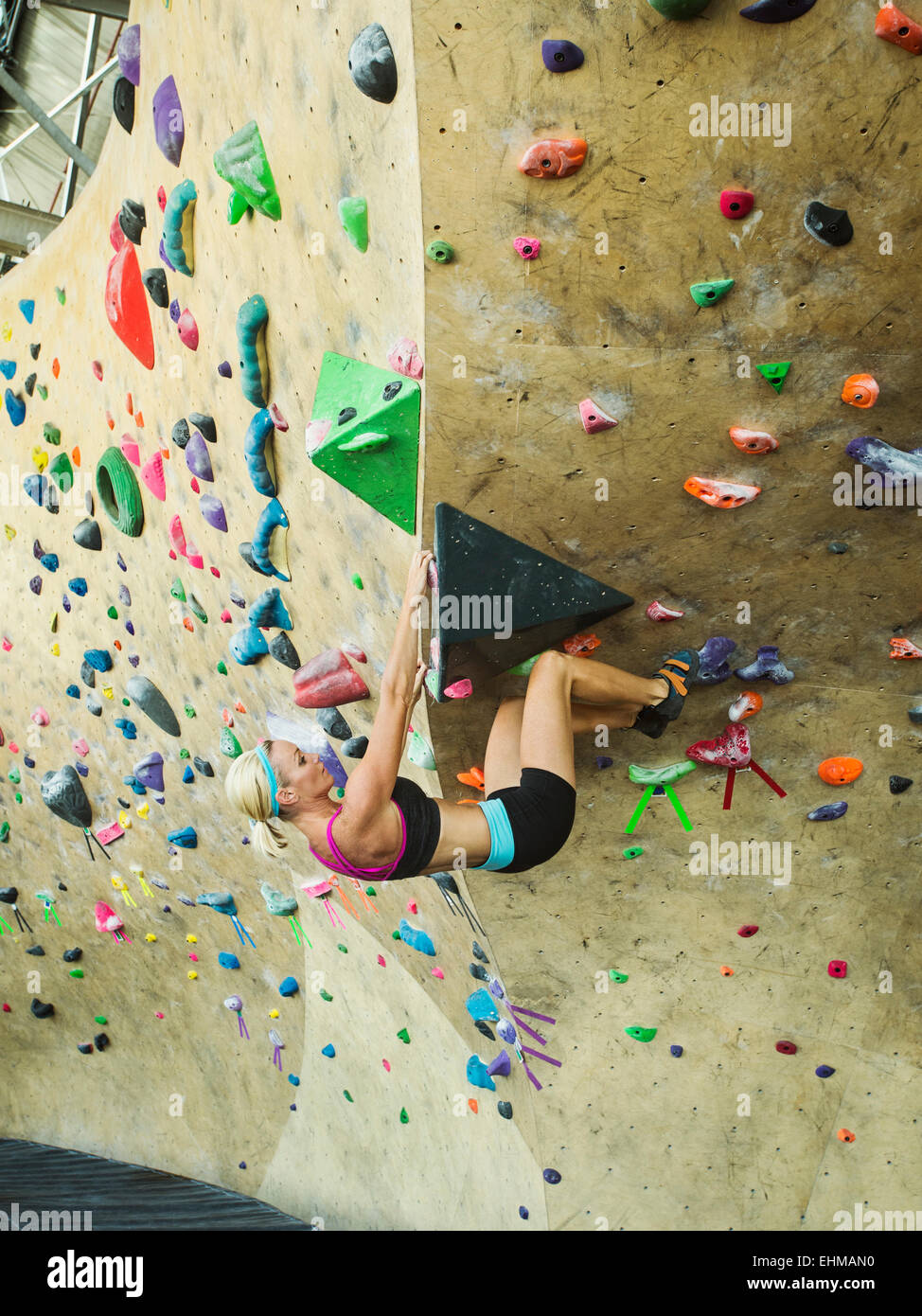 Caucasian woman climbing indoor rock wall Stock Photo