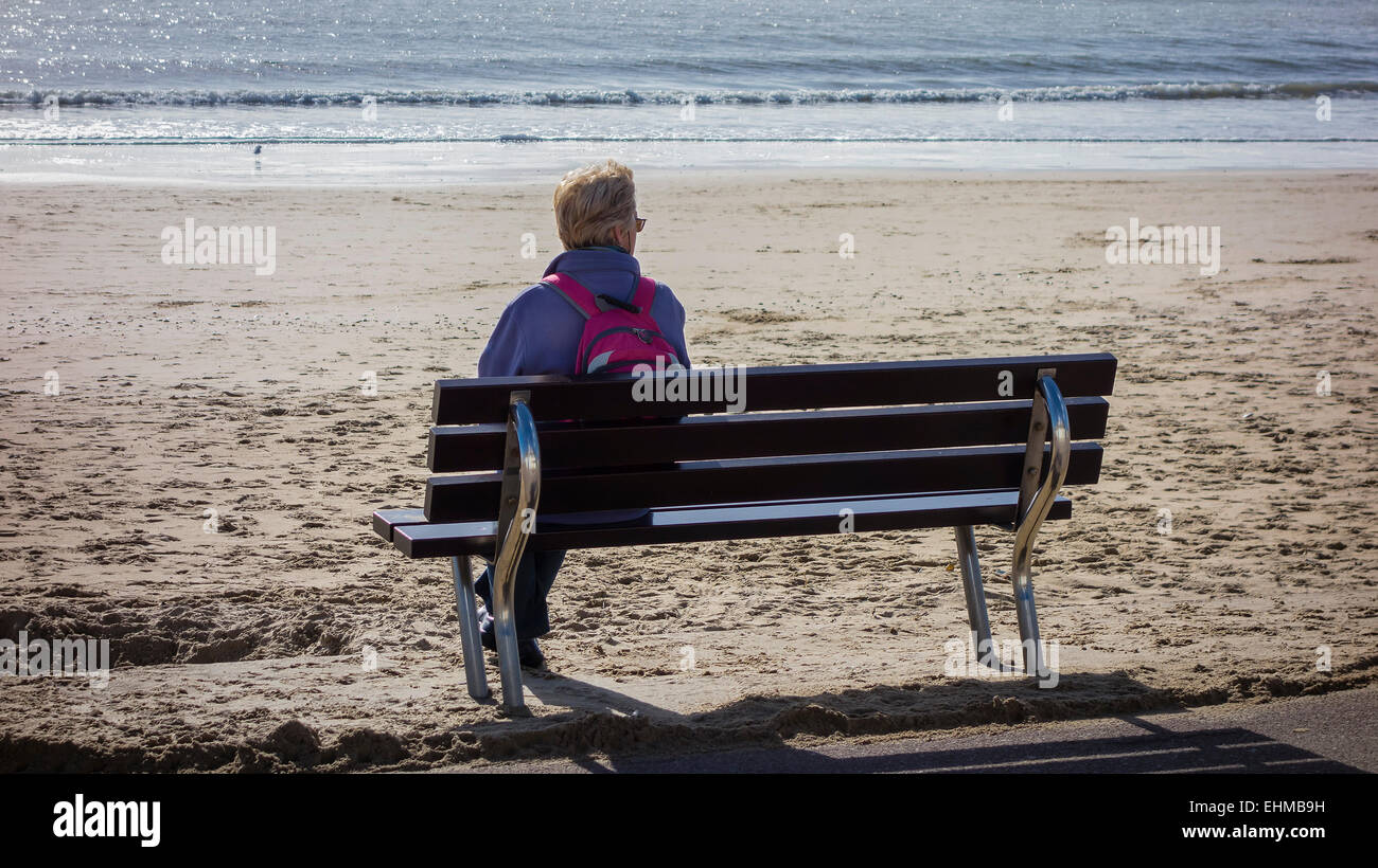 Lady alone on promenade seat at the seaside, West Beach, Bournemouth, Dorset, England, UK Stock Photo