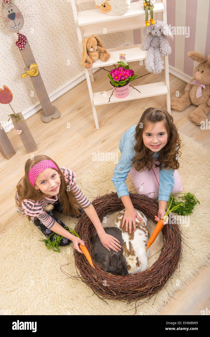 Easter - Little girls stroking the rabbits, the nest Stock Photo