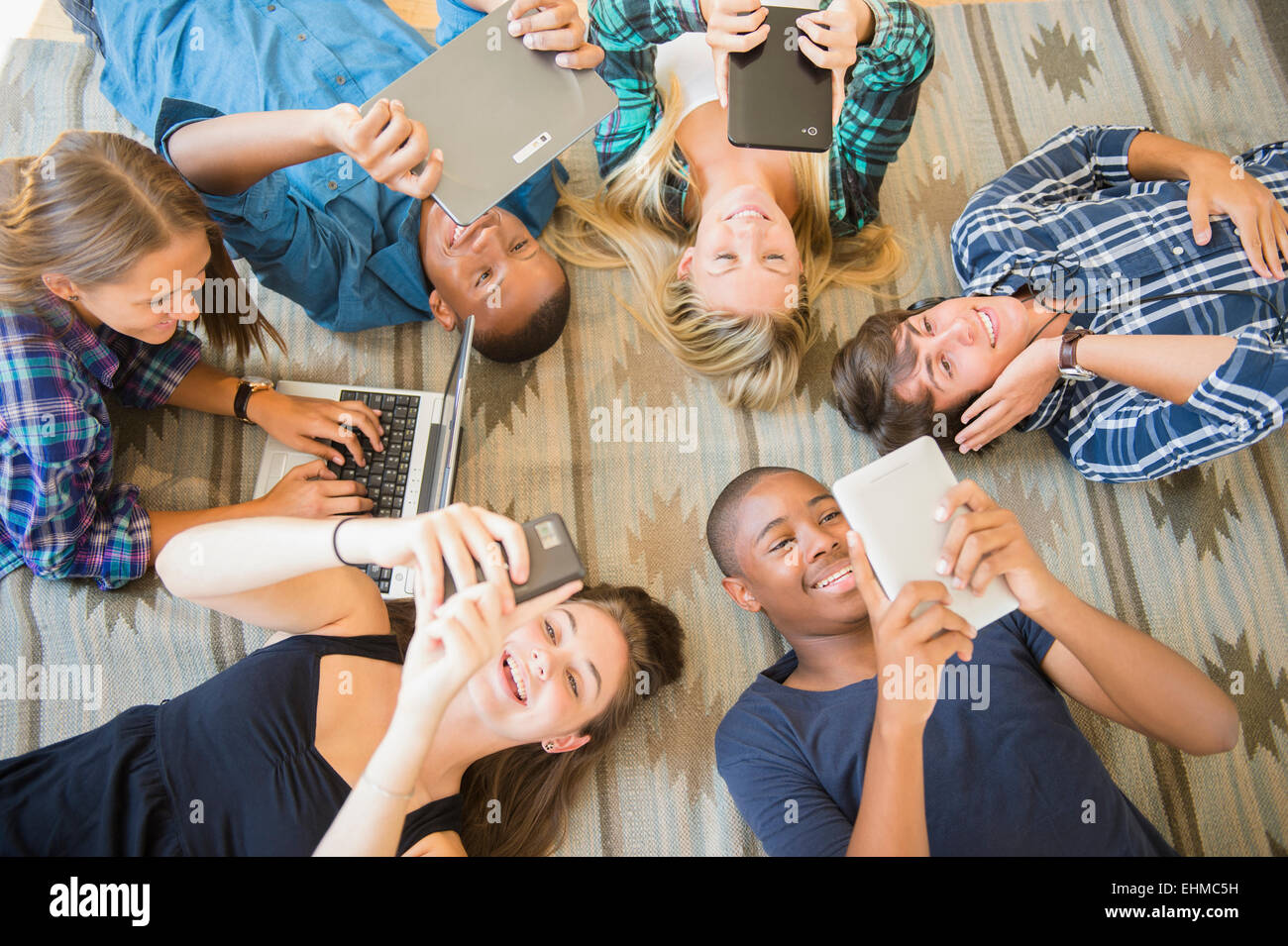 Teenagers laying on floor using technology Stock Photo