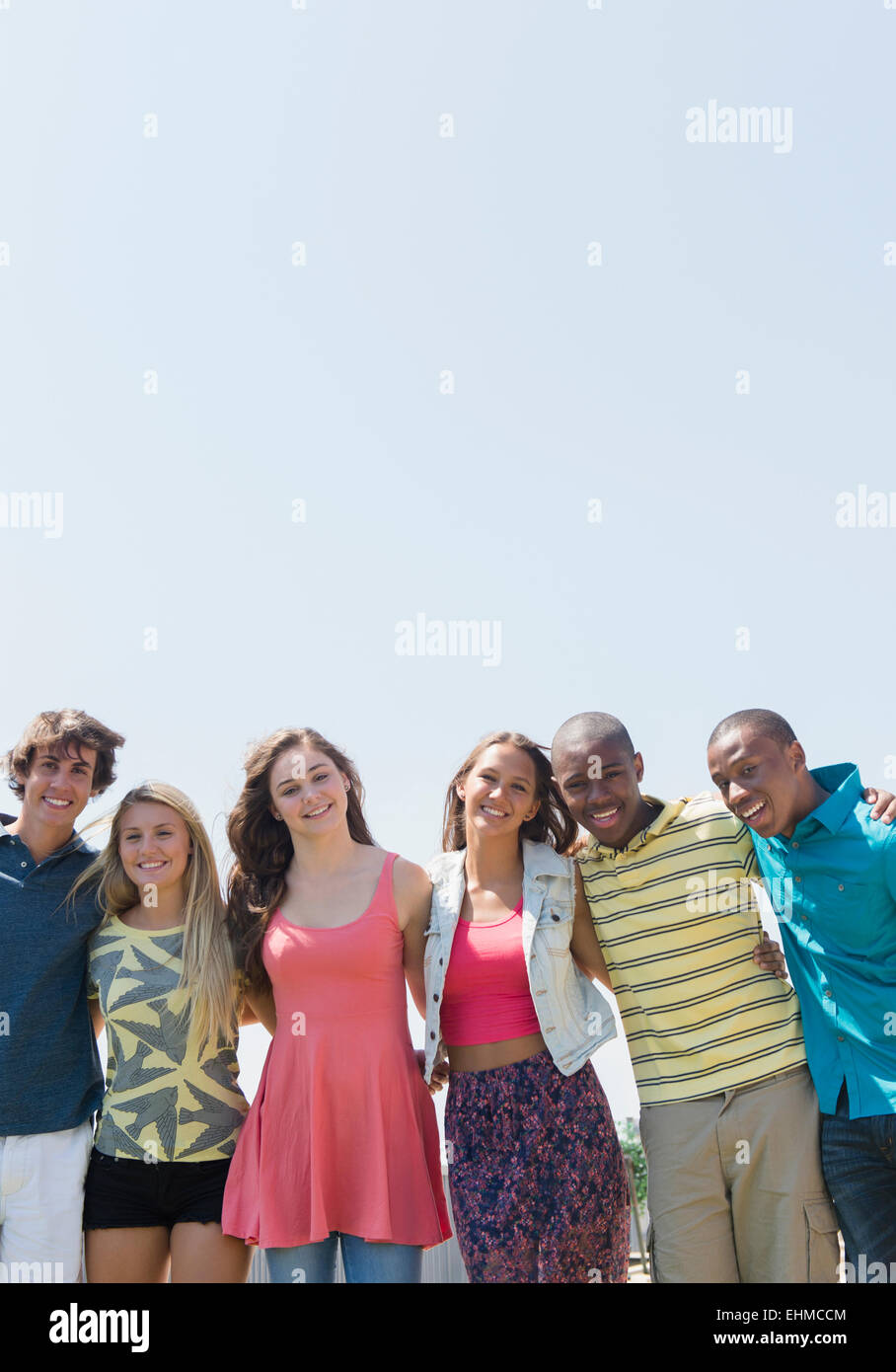 Smiling teenagers hugging under blue sky Stock Photo