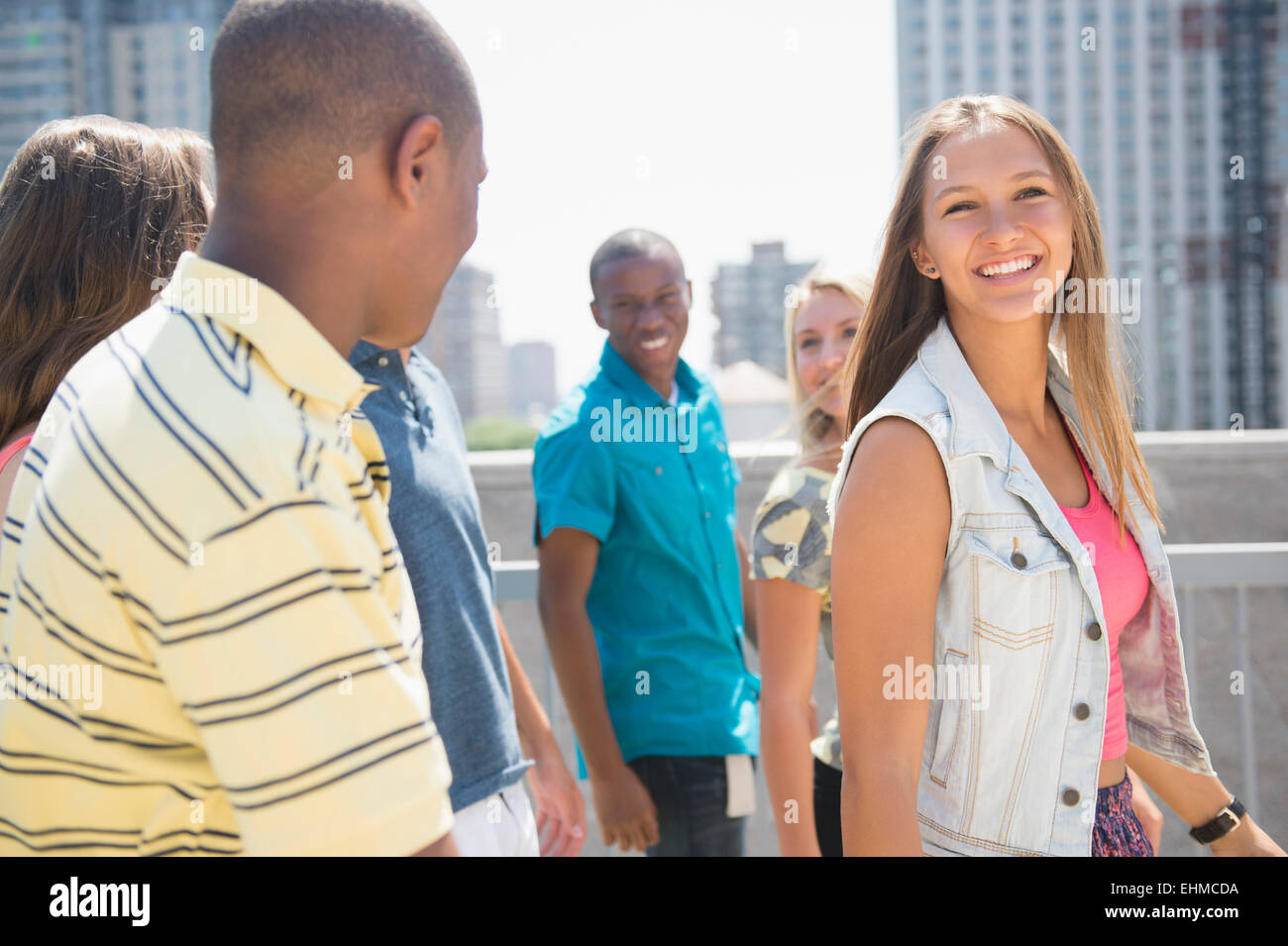 Smiling teenagers walking on urban rooftop Stock Photo