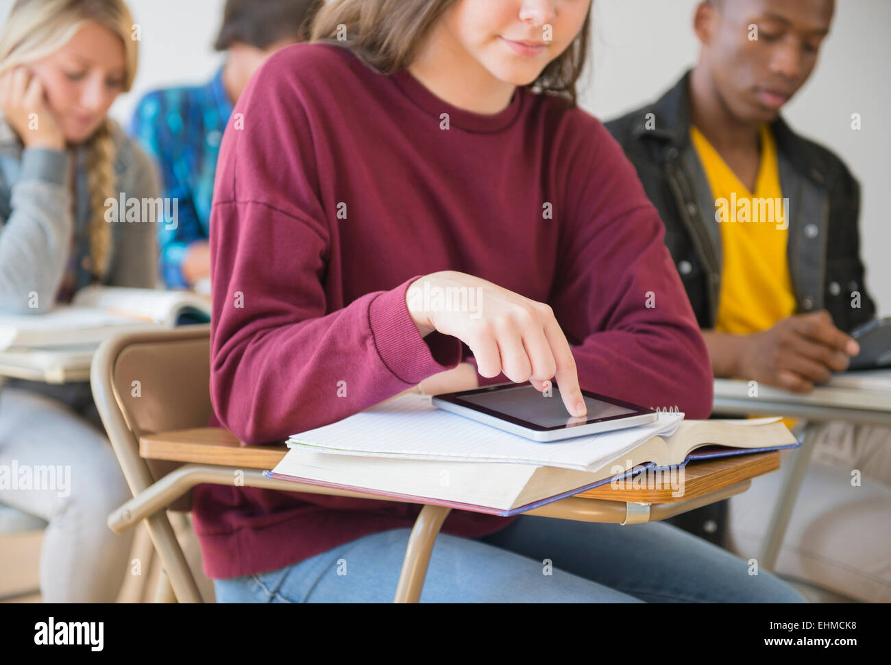 Teenage student using digital tablet on desk in classroom Stock Photo