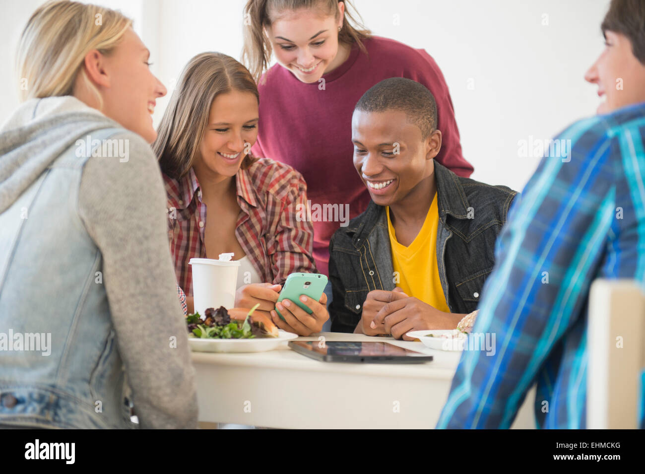 Teenagers using cell phone at table Stock Photo