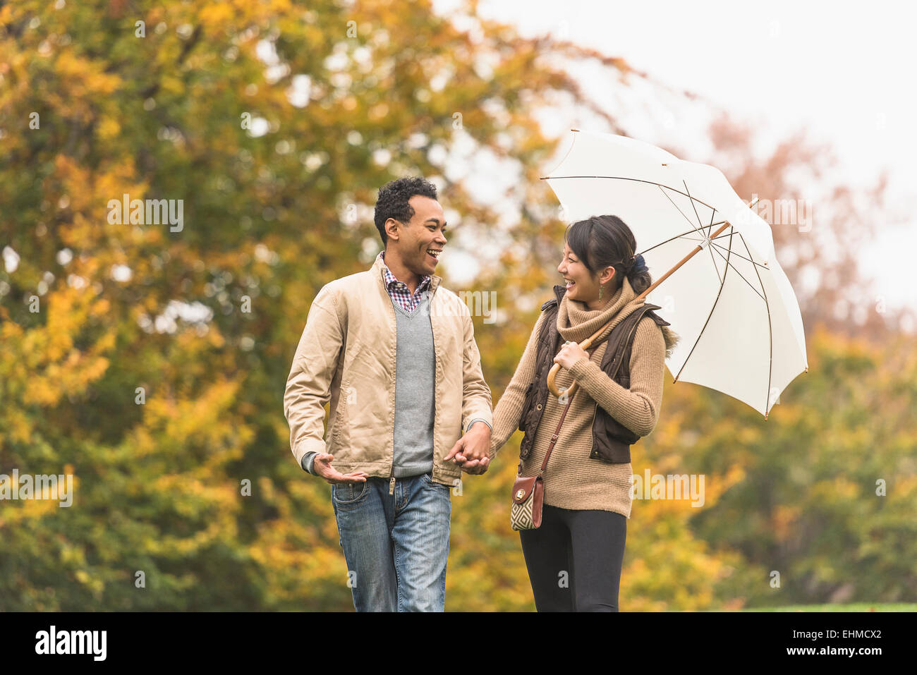 Couple walking with umbrella in park Stock Photo - Alamy