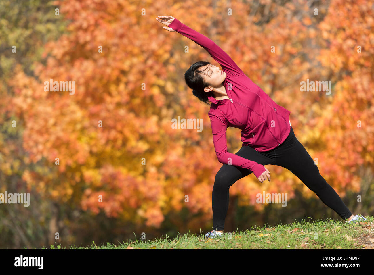 Asian runner stretching in park Stock Photo